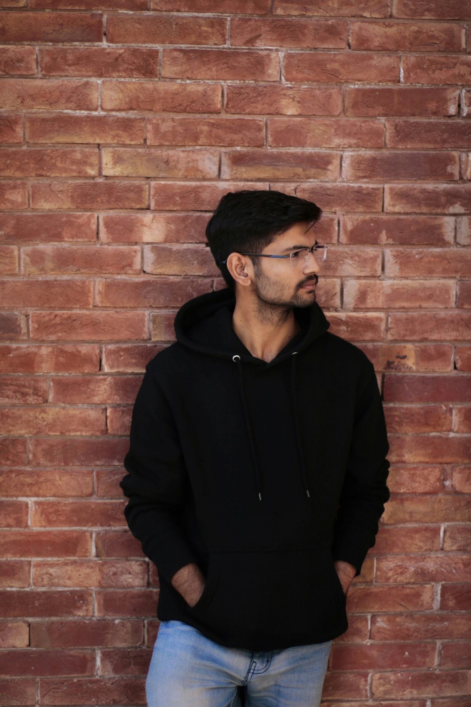 a man standing in front of a brick wall